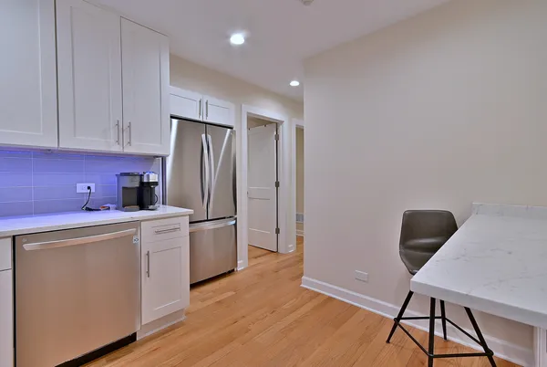 a kitchen with a refrigerator a stove top oven a cabinetry and a potted plant