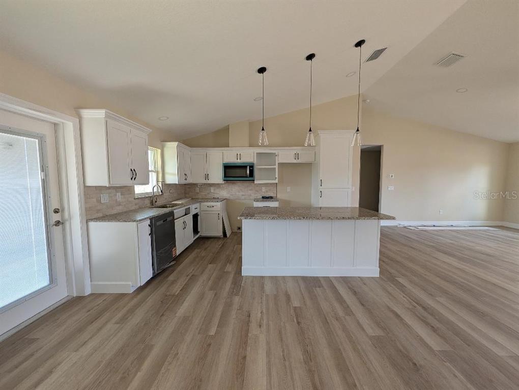 5441 Chestnut Ridge Road Dade City, FL 33523 - Photo 12 of 23 a large kitchen with kitchen island a large counter top a stove and a wooden floors