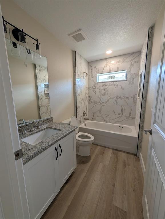 5441 Chestnut Ridge Road Dade City, FL 33523 - Photo 17 of 27 a bathroom with a granite countertop sink a toilet a mirror and shower