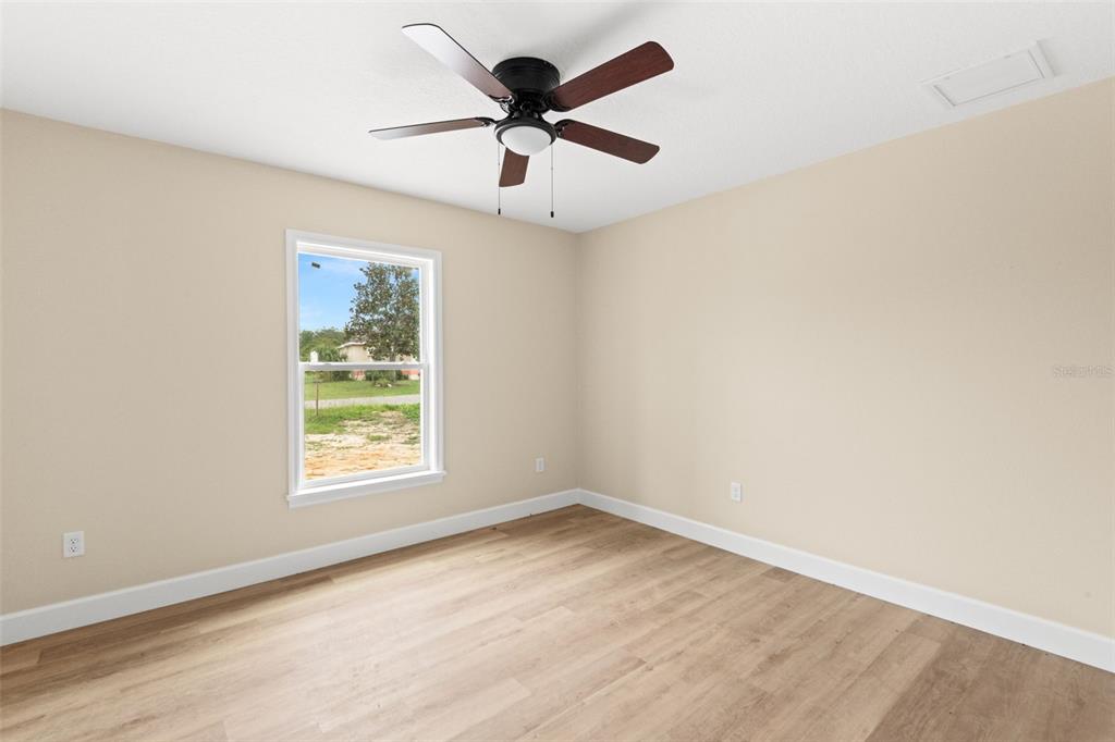 5441 Chestnut Ridge Road Dade City, FL 33523 - Photo 24 of 27 an empty room with wooden floor ceiling fan and windows