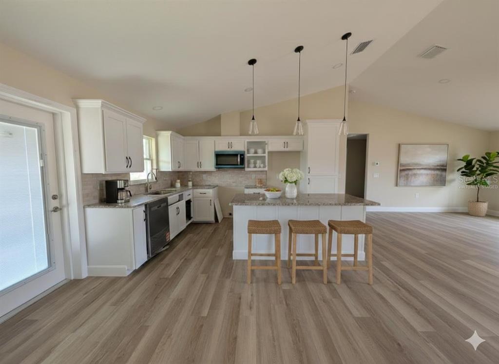5441 Chestnut Ridge Road Dade City, FL 33523 - Photo 4 of 27 a kitchen with stainless steel appliances kitchen island granite countertop a table chairs stove and white cabinets