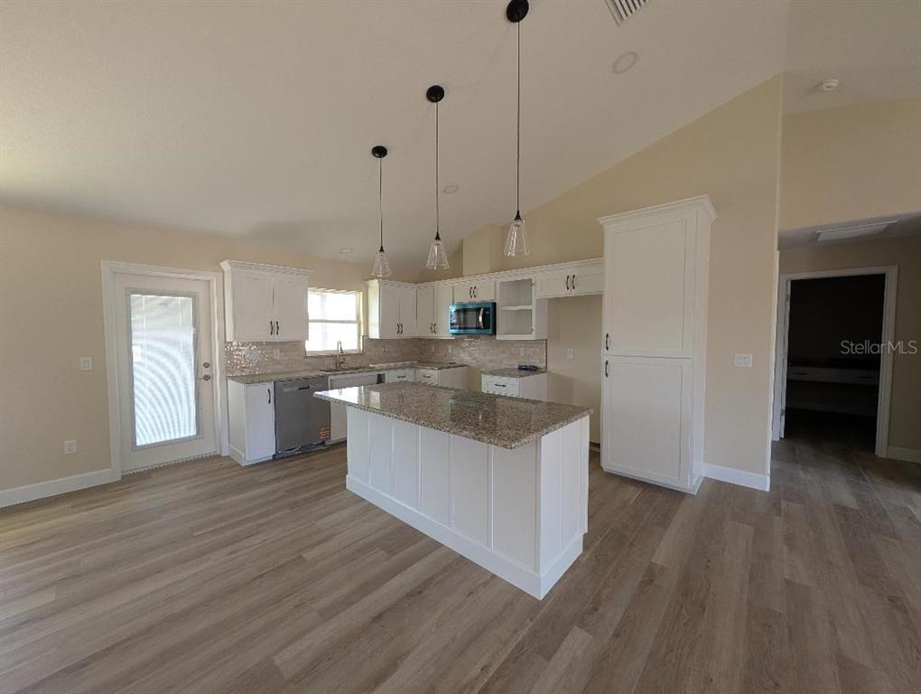 5441 Chestnut Ridge Road Dade City, FL 33523 - Photo 10 of 23 a kitchen with stainless steel appliances granite countertop a sink a stove a refrigerator and white cabinets with wooden floor
