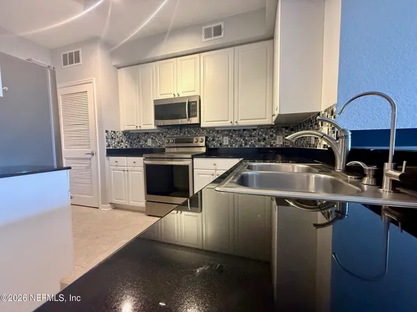 a kitchen with stainless steel appliances a sink a stove a microwave a sink a refrigerator and cabinets