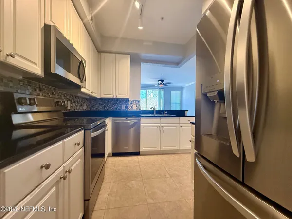a kitchen with stainless steel appliances granite countertop a refrigerator a stove and a sink