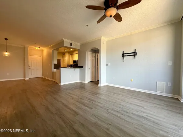 a view of a big room with wooden floor a ceiling fan and windows