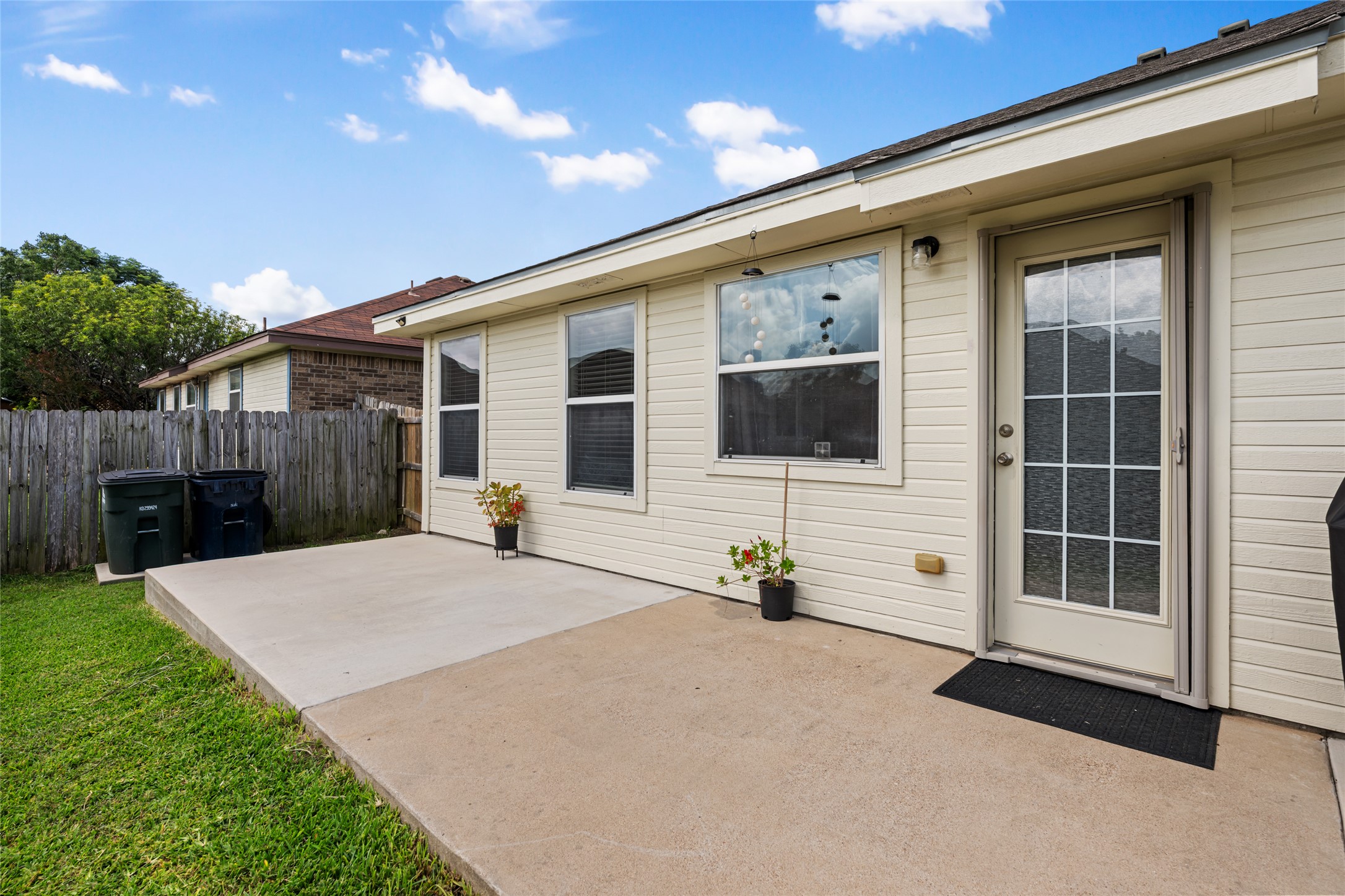 144 Calcite Lane Jarrell, TX 76537 - Photo 30 of 38 A spacious concrete patio awaits outdoor enjoyment, with a full-view glass door providing seamless indoor-outdoor access.