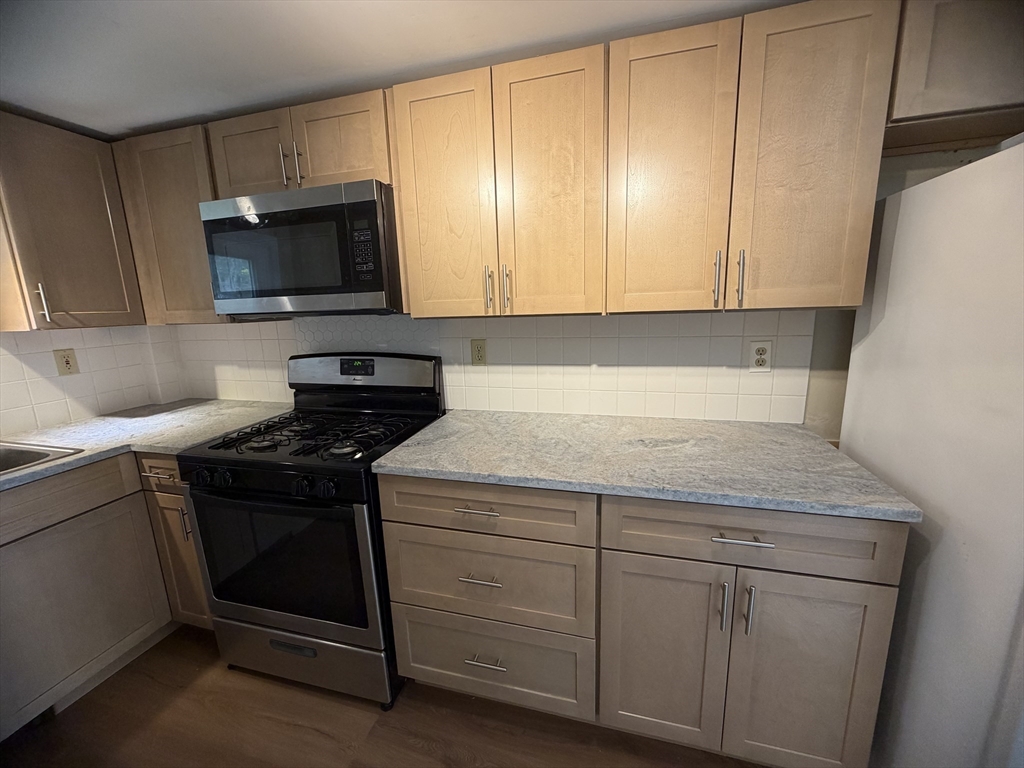 79 North Main Street, Unit A Bellingham, MA 02019 - Photo 9 of 22 a kitchen with white cabinets and a stove top oven