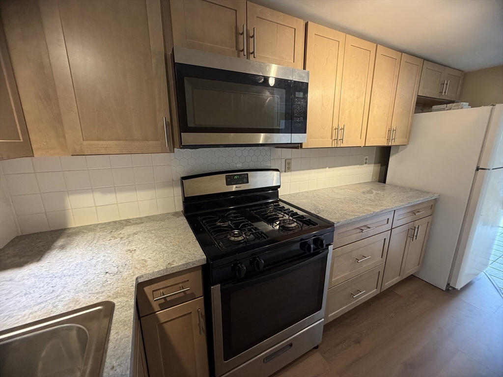 79 North Main Street, Unit A Bellingham, MA 02019 - Photo 10 of 22 a kitchen with granite countertop white cabinets and black appliances