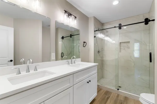 a bathroom with a shower sink vanity mirror and toilet