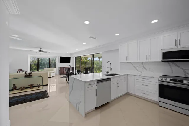 a kitchen that has a lot of white cabinets and stainless steel appliances