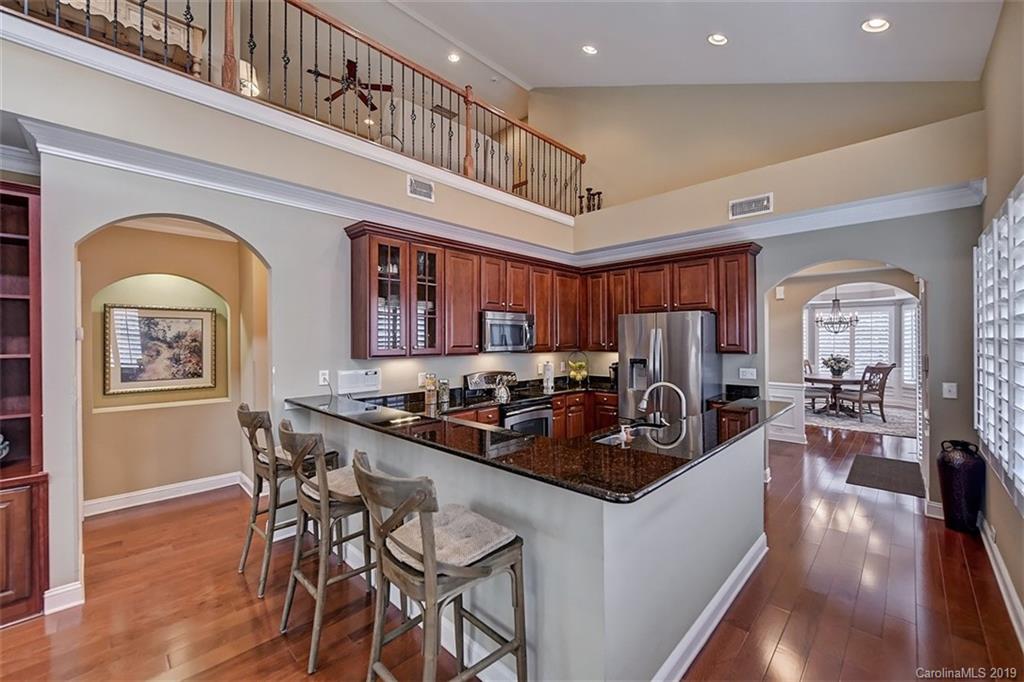 405 Halyard Lane Tega Cay, SC 29708 - Photo 9 of 48 a kitchen with stainless steel appliances granite countertop a stove a refrigerator a dining table and chairs with wooden floor
