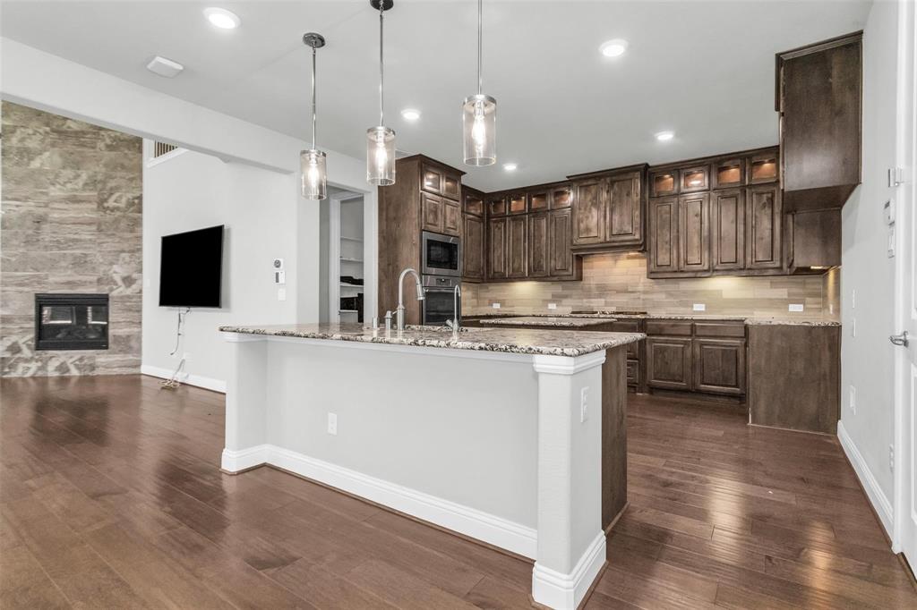 6333 Hall Road Frisco, TX 75034 - Photo 13 of 38 Gourmet kitchen with wood-finish flooring, granite countertops, dark wood cabinetry, and stainless steel appliances