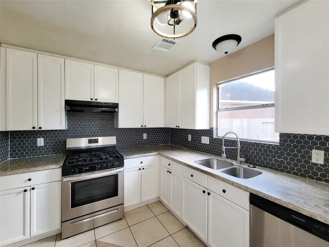 a kitchen with cabinets appliances a sink and a window