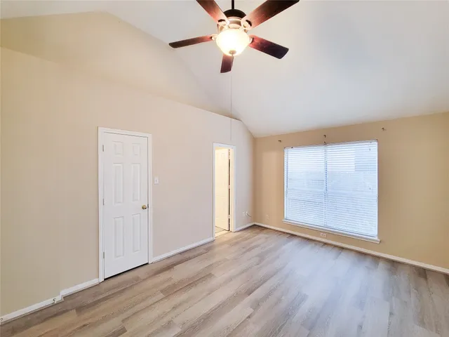 an empty room with wooden floor chandelier fan and windows