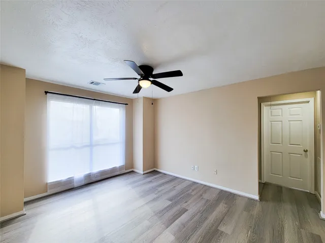a view of empty room with wooden floor and fan