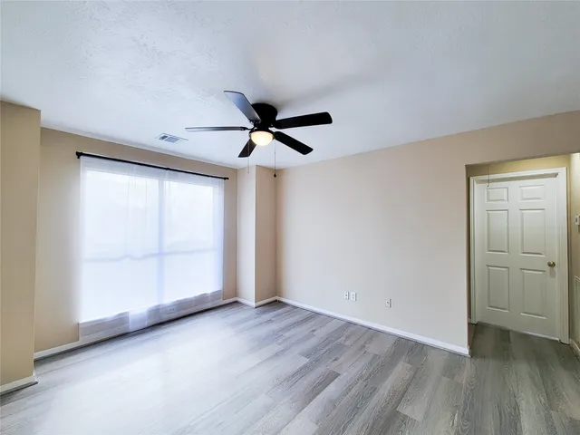 an empty room with wooden floor and windows