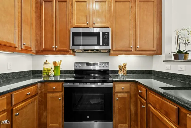 a kitchen with stainless steel appliances granite countertop a stove a sink and a microwave