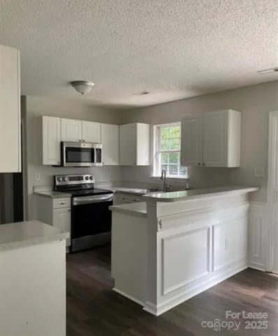 a kitchen with stainless steel appliances granite countertop a stove a sink and a microwave