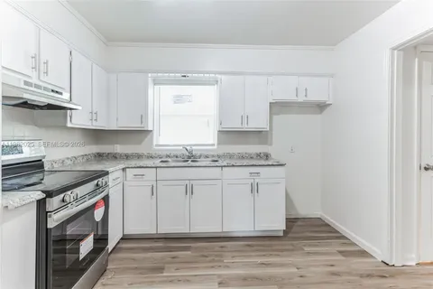a kitchen with granite countertop white cabinets and white appliances