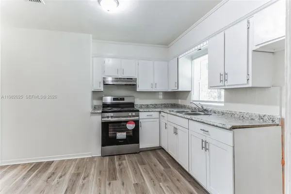 a kitchen with stainless steel appliances granite countertop a stove and white cabinets