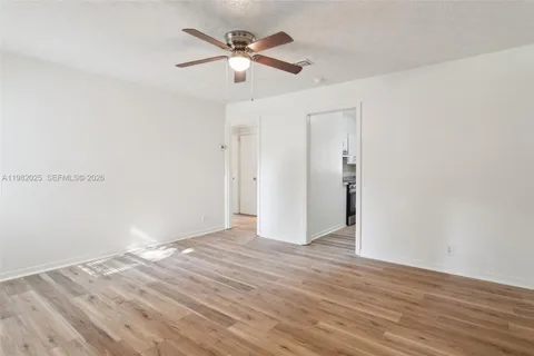 an empty room with wooden floor and ceiling fan