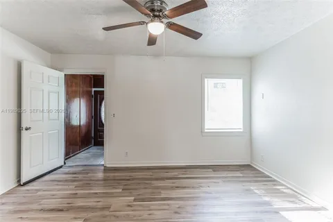 an empty room with wooden floor closet and windows