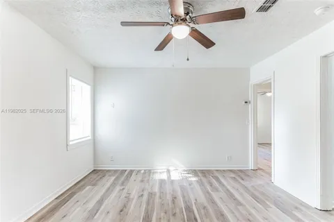 an empty room with wooden floor fan and windows