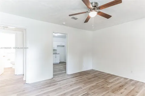 an empty room with wooden floor ceiling fan and windows