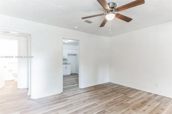 an empty room with wooden floor ceiling fan and windows