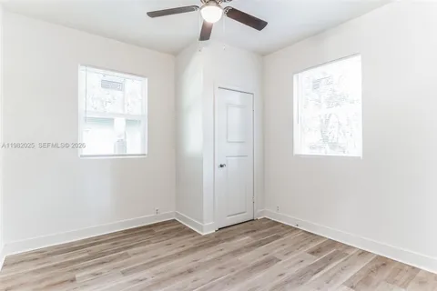 an empty room with wooden floor chandelier fan and windows