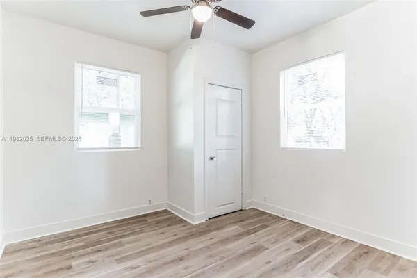an empty room with wooden floor chandelier fan and windows