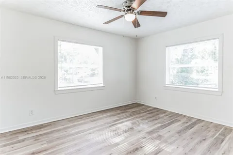 a view of an empty room with a window and wooden floor