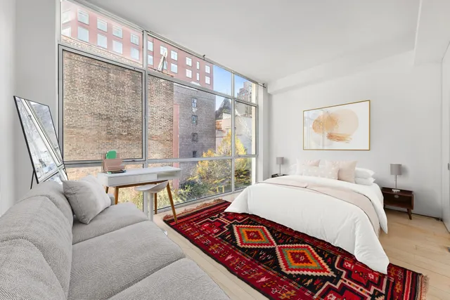 a bedroom with a bed a large window with table and chair