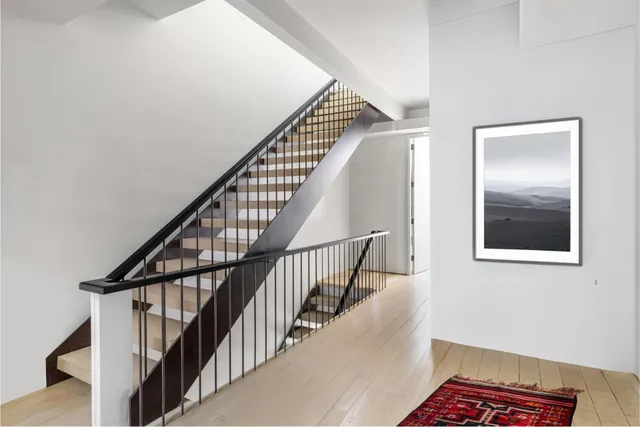a view of staircase with lots of frames on wall and wooden floor