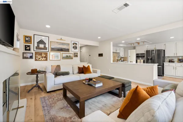 a living room with furniture kitchen view and a flat screen tv