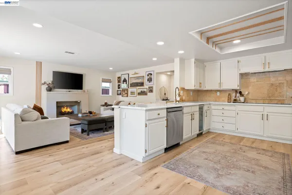 a kitchen with a sink dishwasher a white stove refrigerator and cabinets with wooden floor