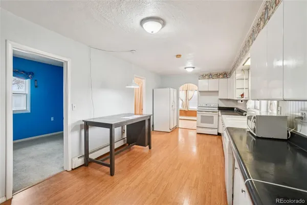 a living room with stainless steel appliances furniture a large window and wooden floor