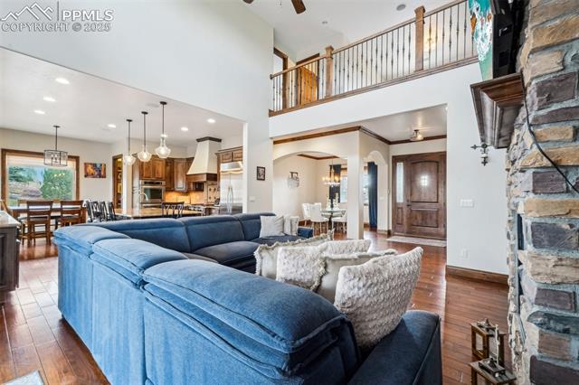 13665 Random Ridge View Colorado Springs, CO 80921 - Photo 7 of 49 Living room featuring dark wood-type flooring, ceiling fan, ornamental molding, and a high ceiling
