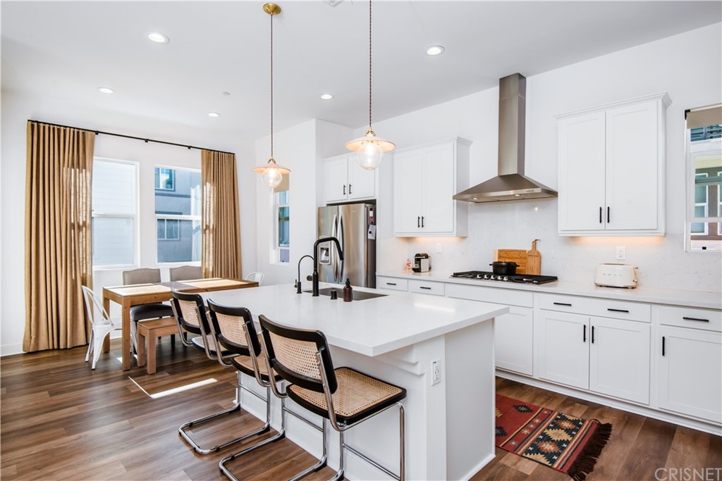 575 Daniel Freeman Circle Inglewood, CA 90301 - Photo 11 of 42 a kitchen with stainless steel appliances granite countertop a stove a sink a oven a dining table and chairs with wooden floor