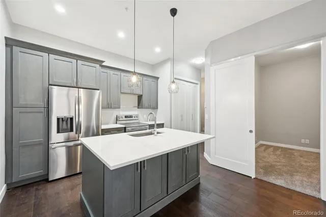 a kitchen with a refrigerator a sink and wooden floor