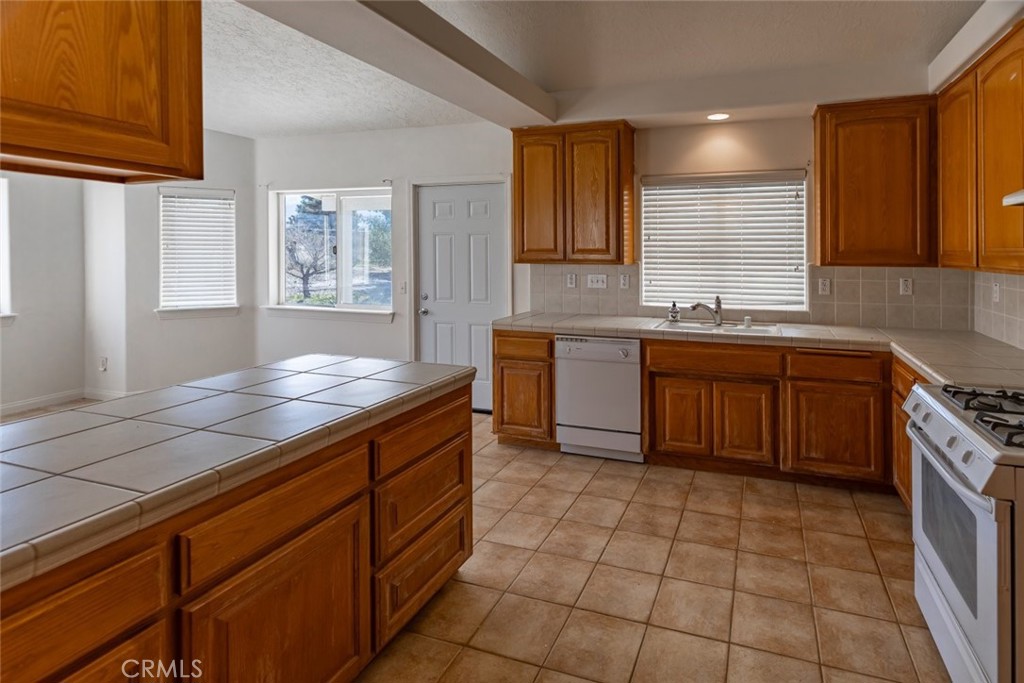 12384 Redwood Road Pinon Hills, CA 92372 - Photo 12 of 35 a kitchen with stainless steel appliances granite countertop a sink counter space cabinets and a large window