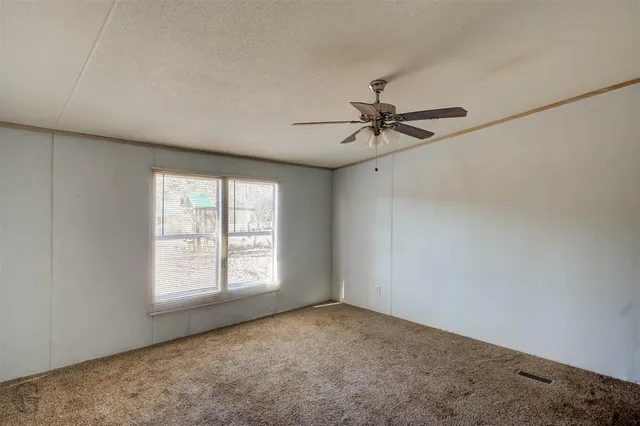 an empty room with a window and a fan