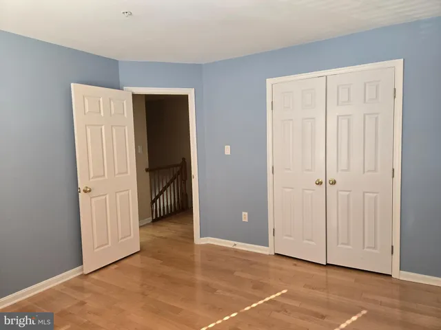 a view of an empty room with wooden floor and a fireplace