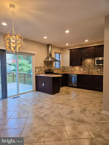 a large kitchen with kitchen island a large counter top and stainless steel appliances