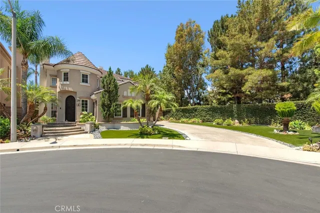 a front view of a house with a garden and trees