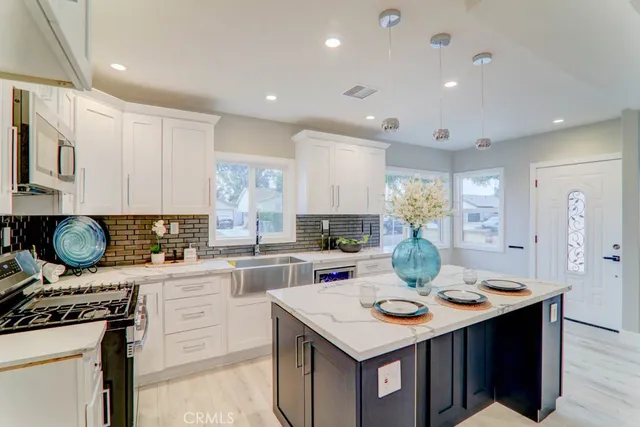 a kitchen with a stove a sink a kitchen island with chairs and wooden floor