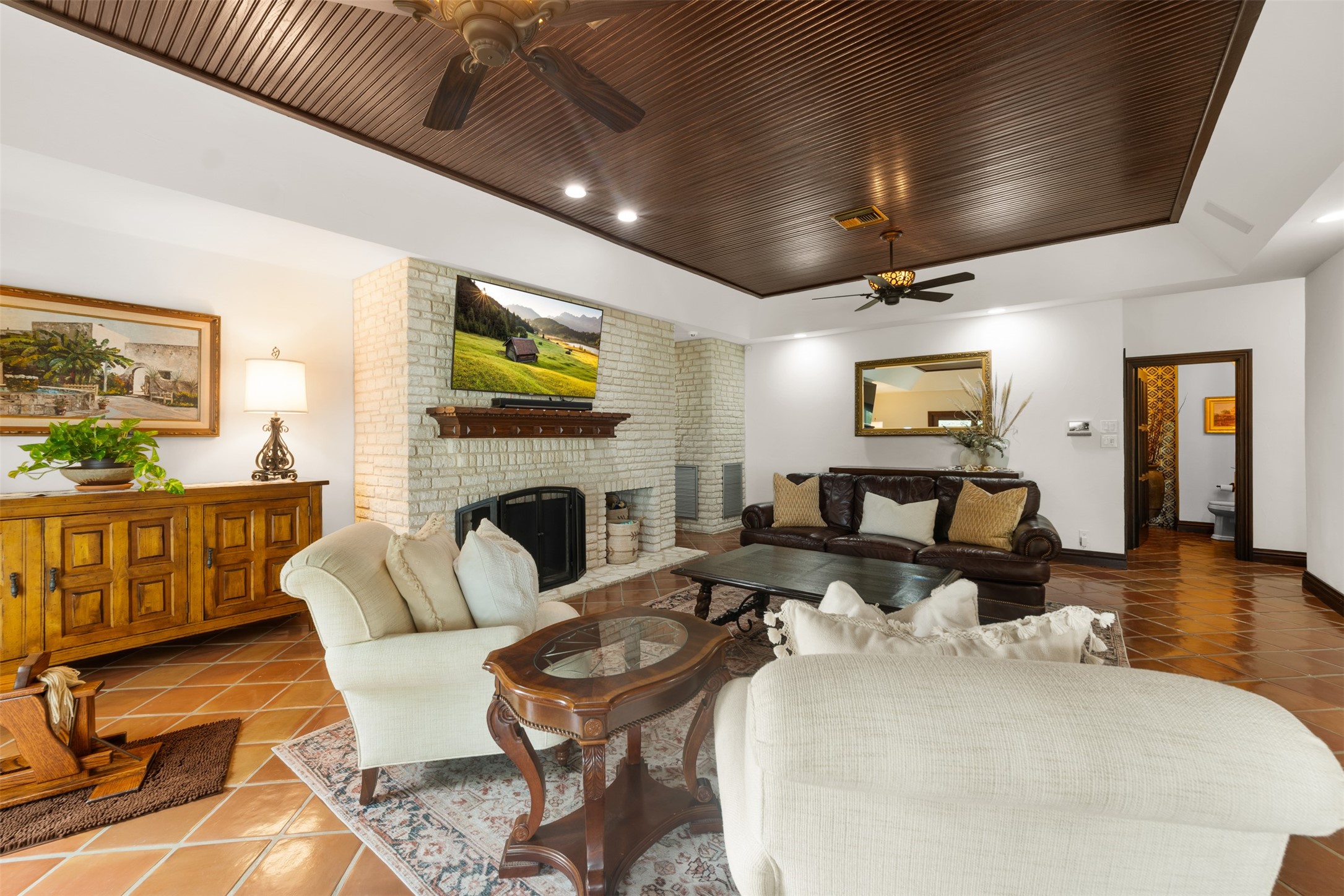 34000 Smithson Valley Road Bulverde, TX 78163 - Photo 10 of 50 The spacious family room offers warm Mediterranean character with terracotta flooring, a striking stone fireplace, and a rich wood-paneled ceiling. Designed for comfortable everyday living and effortless entertaining.