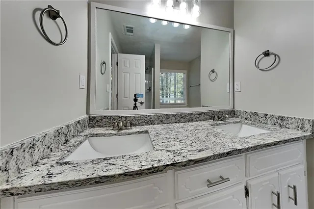 a bathroom with a granite countertop sink and a mirror
