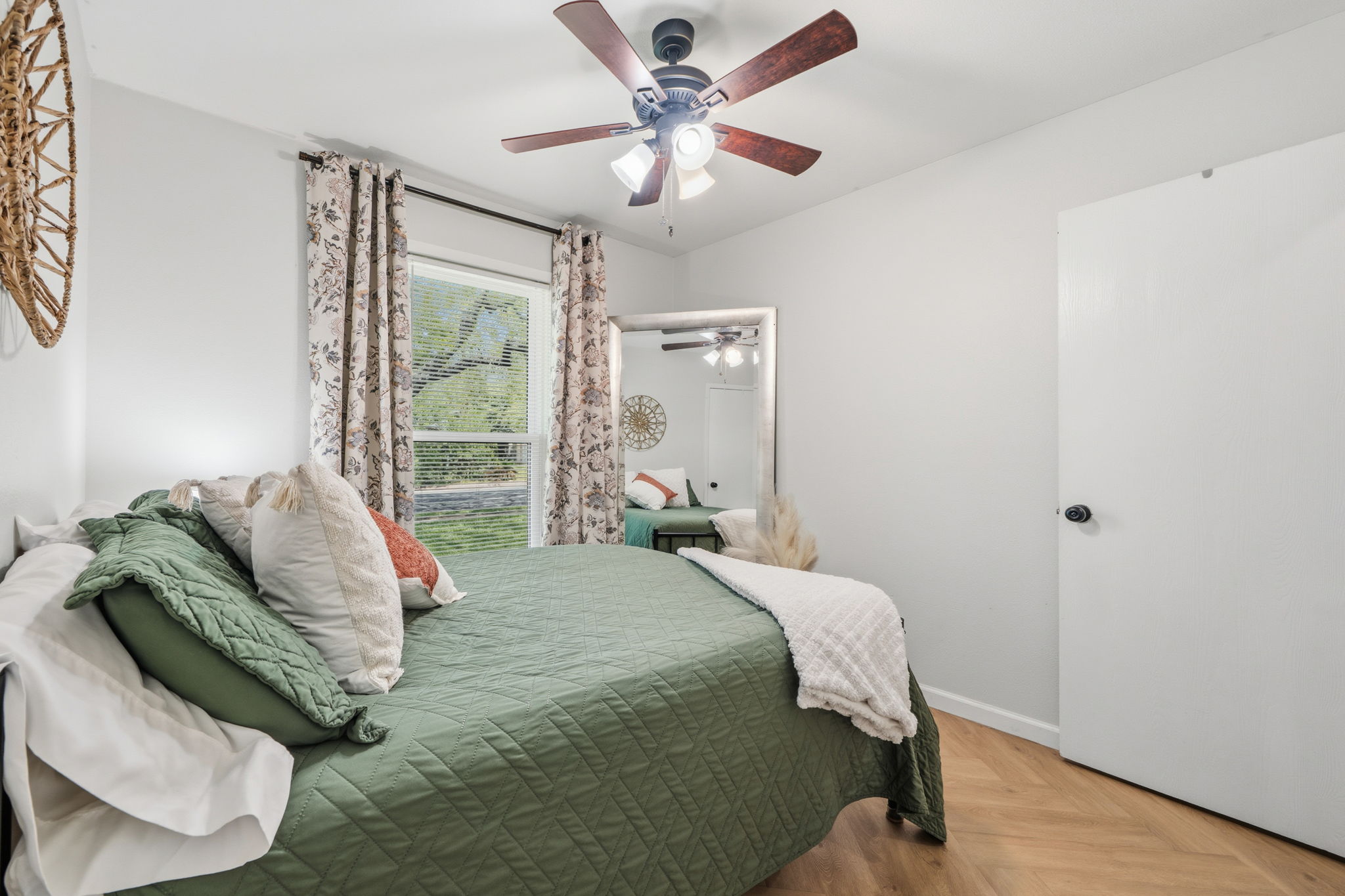 705 Dulwich Street Austin, TX 78748 - Photo 20 of 36 Herringbone pattern flooring grounds this comfortable bedroom, featuring a large window and a functional ceiling fan.