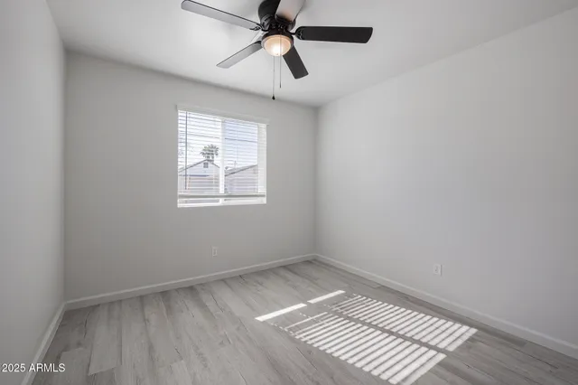 a view of empty room with wooden floor and fan